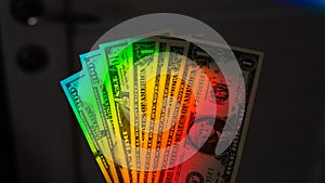 Rays of a rainbow on a man's hand with a bundle of dollars.