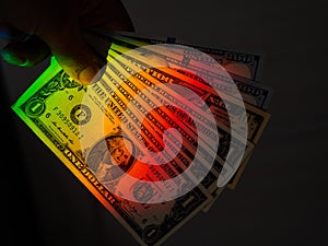 Rays of a rainbow on a man's hand with a bundle of dollars.