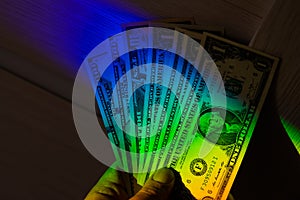 Rays of a rainbow on a man's hand with a bundle of dollars.