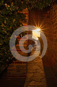 The rays of the setting sun shine through the narrow long arch of the building of the monastery on Mount Athos