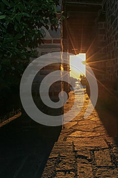 The rays of the setting sun shine through the narrow long arch of the building of the monastery on Mount Athos