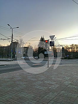 The rays of the setting sun on the streets of the metropolis. Crossroads with traffic lights. City environment.