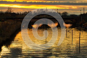 Sunset on river under ancient railway bridge
