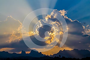 Rays of sun shine through the clouds on blue sky