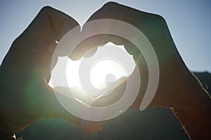 The rays of the sun shine through a symbolic heart made of folded male hands. Dahab, South Sinai Governorate, Egypt