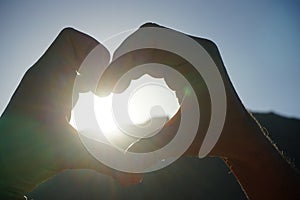 The rays of the sun shine through a symbolic heart made of folded male hands. Dahab, South Sinai Governorate, Egypt