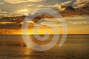 Rays of sunlight behind the clouds above the ocean at sunset