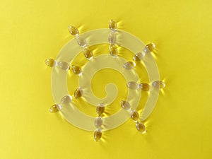 Rays of sunshine from vitamin D capsules on a yellow background.