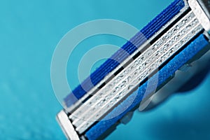 Razor blades on a blue background with drops of icy water