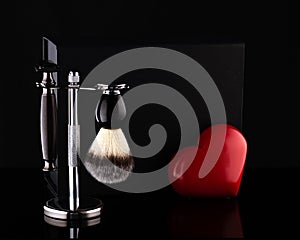 Razor and brush on stand and black box, red heart on black ackground