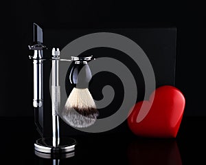 Razor and brush on stand and black box, red heart on black ackground