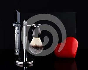 Razor and brush on stand and black box, red heart on a black background