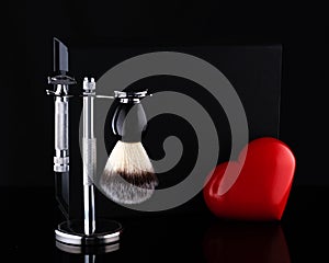 Razor and brush on stand and black box, red heart on black background