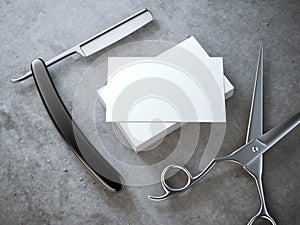 Razor and scissors with stack of blank business cards