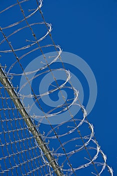 Razor wire security fence and a blue sky