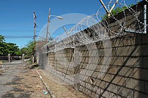 Razor wire at top of a high, grey, brick wall protecting entrance to private property in Kingston, Jamaica.