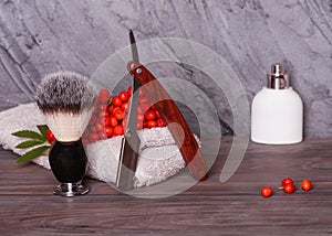 Razors, brush, towels, perfume and rowan on wood background