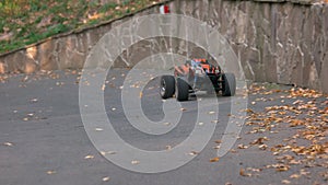 RC monster truck rides on the road and blows up leaves.