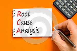 RCA root cause analysis symbol. Concept words RCA root cause analysis on white note. Businessman hand. Beautiful orange table