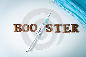 3rd covid vaccine booster shot concept with face mask. Syringe is seen on table as a concept for the 3rd covid-19 vaccine dose,