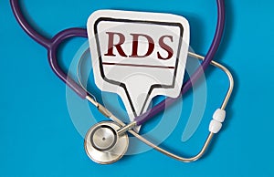 RDS - acronym on white figure sheet on a blue background with a stethoscope photo