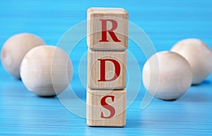 RDS - acronym on wooden cubes on a blue background with wooden round balls