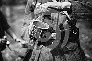 Re-enactor Dressed As World War II German Wehrmacht Soldier Holds Flask With Water. Photo In Black And White Colors