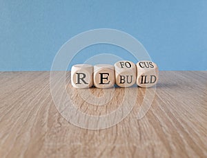 Re focus and re build symbol. Businessman turns cubes and changes the word \'refocus\' to \'rebuild\'