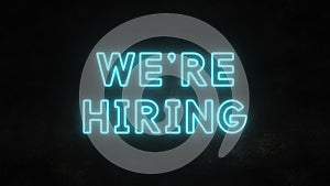 We`re hiring bright neon text on a dirty wall