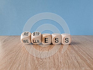 Re str ess for we lln ess symbol. Concept words Restress and Wellness on wooden cubes