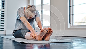 Reach out as far as you can. Shot of a relaxed mature woman practicing yoga inside of a studio during the day.