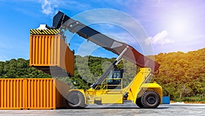 Reach stacker yellow forklift truck handling shipping container in business import export logistic shipping yard with cargo