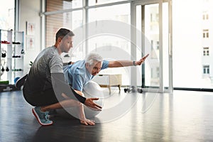 Reach for a stronger you. a young male physiotherapist assisting a senior patient in recovery.