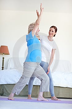 Reaching for that fitness goal - Senior Health. Full-length of an elderly woman doing stretches with her fitness trainer