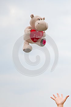 Reaching out for a soft toy holding a red heart I love you.