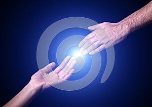 Reaching and touching hands. Bright light star flare with touching fingertips.