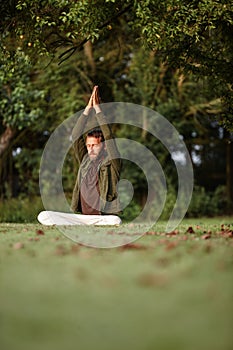 Reaching towards transcendence. a handsome mature man doing yoga in the outdoors.