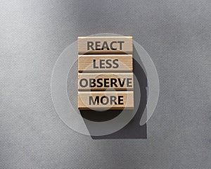 React less Observe more symbol. Wooden blocks with words React less Observe more. Beautiful grey background. Business and React