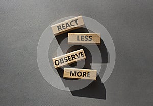 React less Observe more symbol. Wooden blocks with words React less Observe more. Beautiful grey background. Business and React