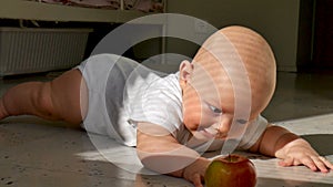 Reaction a six months old baby boy with apple lying on the floor