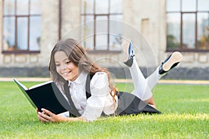 Read every day. Cute small child read library book on green grass. Adorable little girl learning to read at leisure