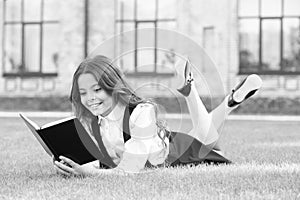 Read every day. Cute small child read library book on green grass. Adorable little girl learning to read at leisure