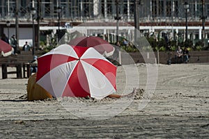 Read and white colors on a beach umbrella protecting family on Coronado beach