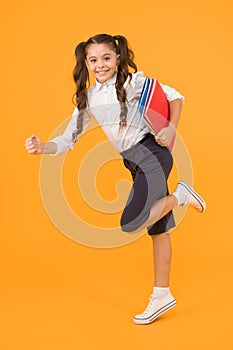 Reader rushing for books. Happy little girl holding books with colorful covers on yellow background. Cute small child