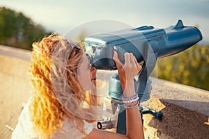 Readhead 30s woman looking through telescope while sightseeing