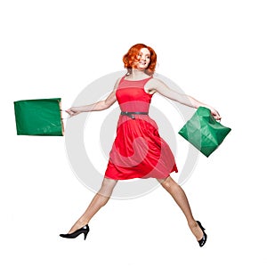 Readhead with green shopping bags jumping