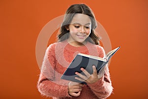 Reading activities for kids. Girl hold book read story over orange background. Child enjoy reading book. Book store