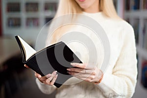 Reading book in library. Student in the library with a book in her hands.