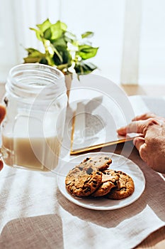 Reading a book at the morning table with a cup of milk and cookies