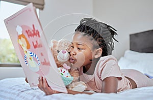 Reading, book and teddy bear with a black girl in bed, lying down to relax in the bedroom with her hobby. Children